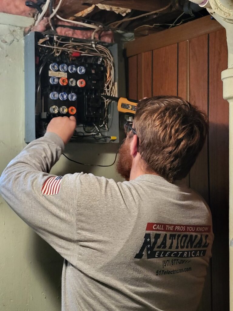 An electrician from National Electric - Lansing working on an indoor electrical panel in Lansing, MI.