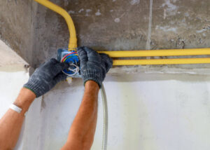 An electrician's hands working on wiring inside an electrical junction box with conduits for BrotherlyLove Electric LLC in Houston, TX.