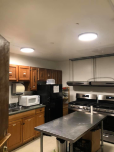 An electrician working on a large rectangular light fixture in a kitchen for DNA Electrical in Richmond, VA.
