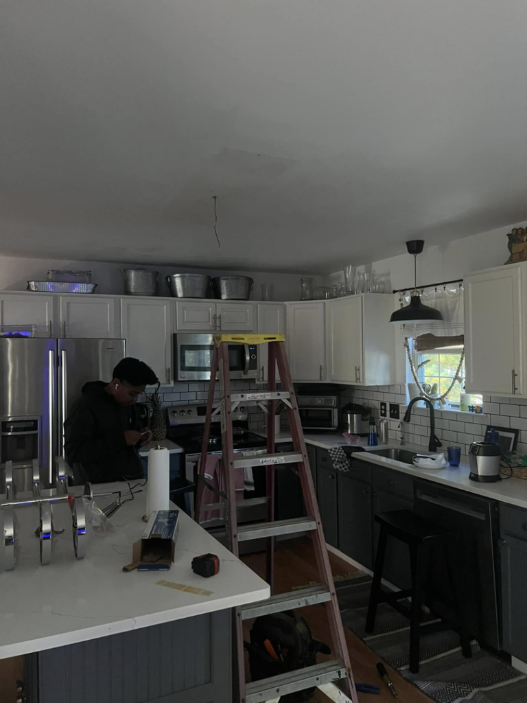 An electrician from PnP Electric working on ceiling wiring for a new light fixture installation in a kitchen in Middletown, DE.