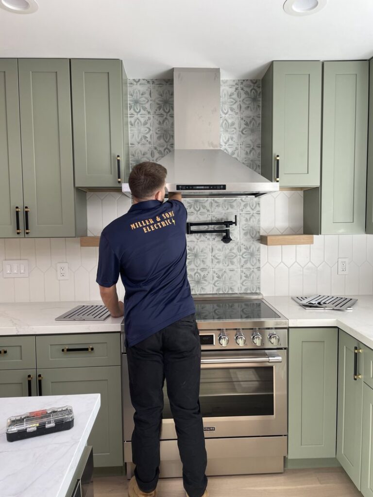 An electrician working on the installation of a kitchen range hood, a service by Miller and Sons Electric in North Myrtle Beach, SC.