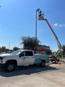 An electrician from Shark Electric using a boom lift to work on a tall light pole in Houston, TX.