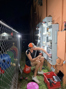 An electrician from The GOAT Electric Company working on an outdoor electrical meter panel at night in Ft Myers, FL.