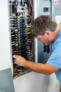 An electrician from Moser Electric working on an open electrical panel, connecting wires in Wisconsin Rapids, WI.