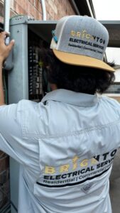 An electrician from Brighton Electrical Services working on an outdoor breaker box in Laredo, TX.