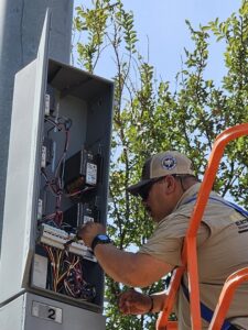 An electrician from Brighton Electrical Services working on an outdoor electrical box in Laredo, TX.