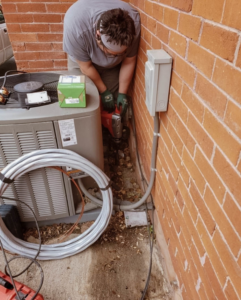 An electrician working on an outdoor electrical box and wiring next to an HVAC unit for Eon Electric in Orem, UT.