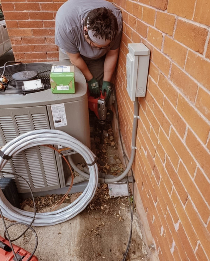 An electrician working on an outdoor electrical box and wiring next to an HVAC unit for Eon Electric in Orem, UT.