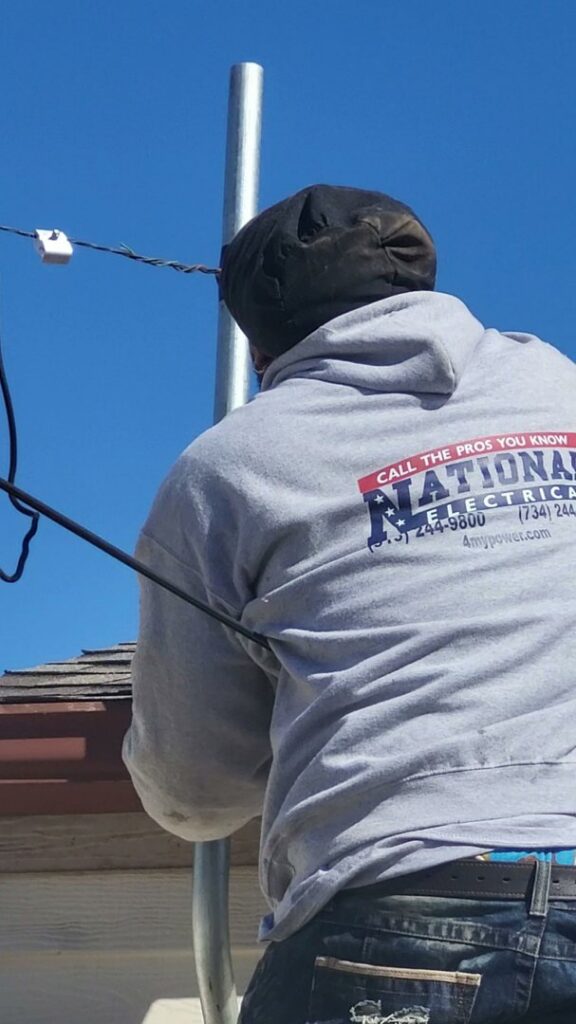 An electrician from National Electric - Lansing working on outdoor electrical lines in Lansing, MI.