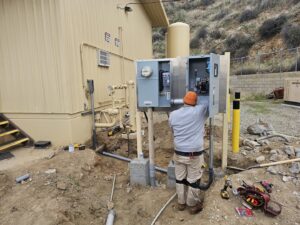 An electrician working on an outdoor commercial electrical panel installation for B&C Electric LLC in Bakersfield, CA