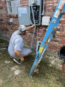 An electrician working on an outdoor electrical panel on a brick house for Justin Benevage Electrical, LLC in Lake Charles, LA
