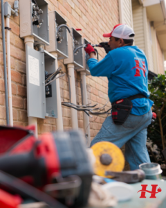An electrician from Powered By H working on outdoor electrical panels and wiring in Houston, TX.