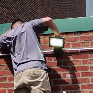 A close-up of an electrician working on an outdoor light fixture for C&J And Sons Multi Services in Newark, NJ.