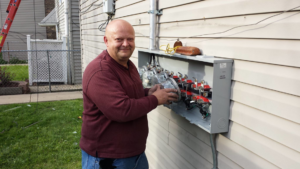 An electrician working on an outdoor electrical meter box for Johns Electric Troubleshooting in Chicago, IL
