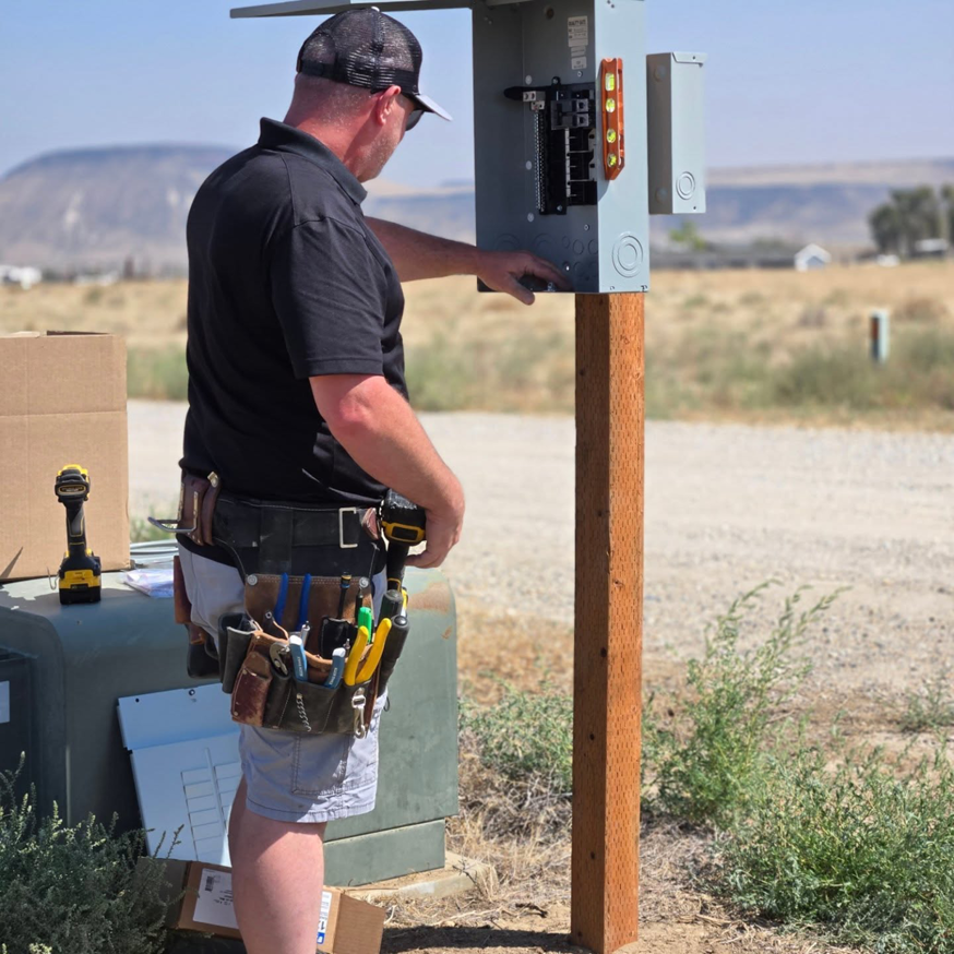 An electrician from Balanced Electric LLC working on an outdoor electrical panel in Caldwell, ID.