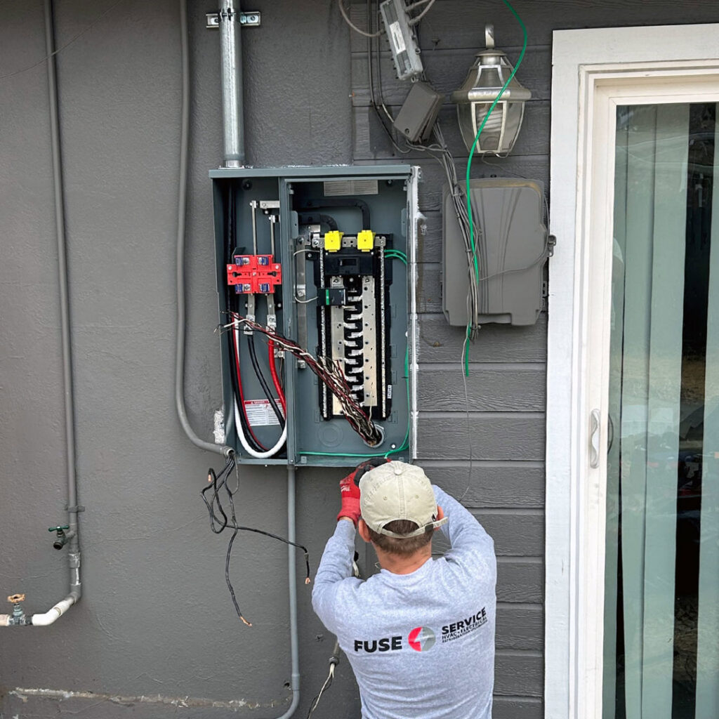 An electrician from Fuse Service working on an outdoor electrical panel in Sacramento, CA