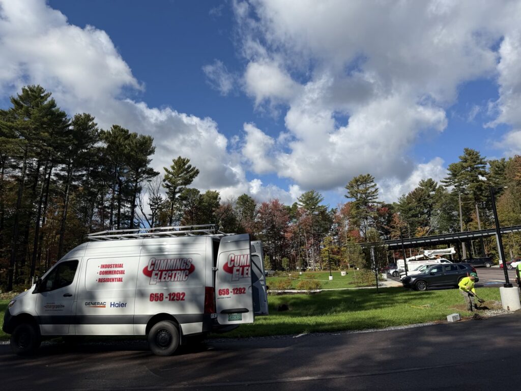 An electrician from Cummings Electric working on outdoor wiring near solar panels in South Burlington, VT.