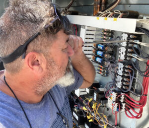 An electrician working on an open electrical control panel with a screwdriver for Ace Electric Inc. in Valdosta, GA.