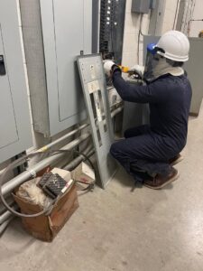 An electrician in full safety gear working on an electrical panel for AVA Electric, LLC in Fort Worth, TX.