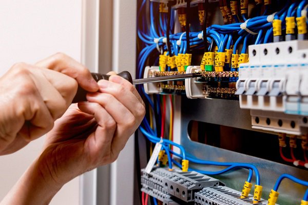 An electrician's hands using a screwdriver to tighten electrical connections within a panel, a service provided by Legacy Electric in Westminster, CO.