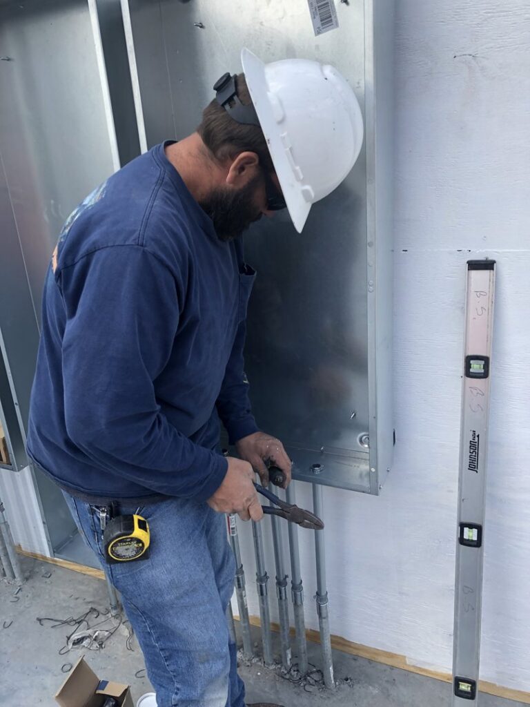 An electrician in a hard hat working on an electrical panel for Erbert Electric in Overland Park, KS