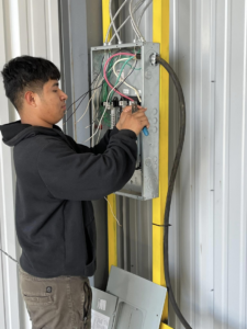 An electrician from K3 Electrical Company Inc working on an electrical panel, connecting wires in Lafayette, LA.