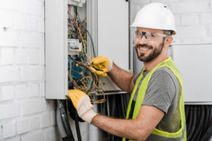 A smiling electrician from Mills Electric Co., Inc. working on an electrical panel in Sumter, SC.