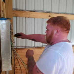 An electrician from Swaim's Electrical Services working on an electrical panel with wires in Wilmington, NC.