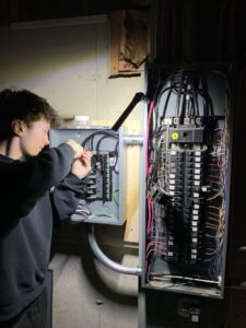 An electrician working on an electrical panel for Tritan Services LLC in Naperville, IL