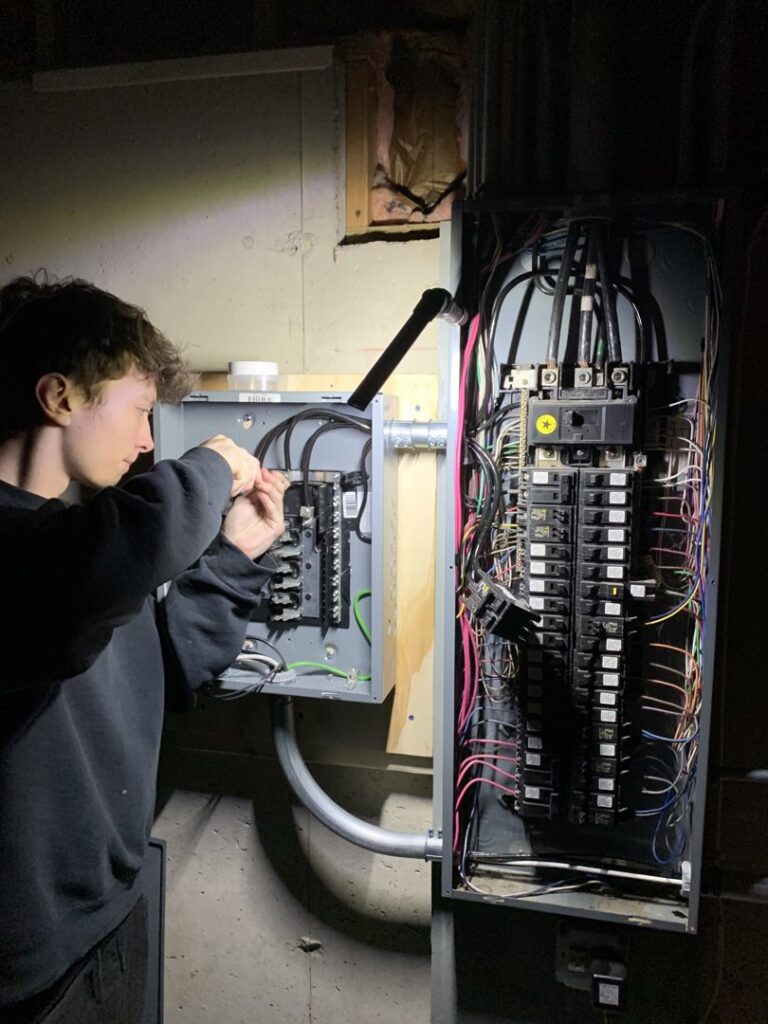 An electrician working on an electrical panel for Tritan Services LLC in Naperville, IL