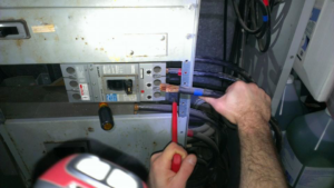 An electrician's hands carefully working on wiring inside an electrical panel for 615 Electric in Nashville, TN