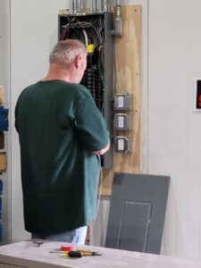 An electrician from FOXX & Hounds Electric working on wiring an electrical panel in Sioux City, IA.