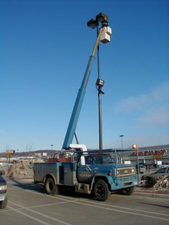 An electrician from Line Electrical Contractors Inc. working on a parking lot light pole with a bucket truck in Waterbury, CT
