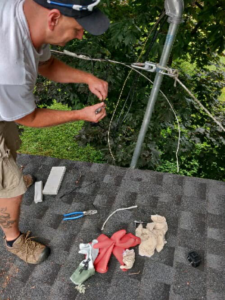 An electrician from Lindquist Electric working on roof wiring and service lines in Upton, MA.