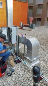 An electrician working on rooftop HVAC unit wiring and conduit for Turn It On Electric in Phoenix, AZ