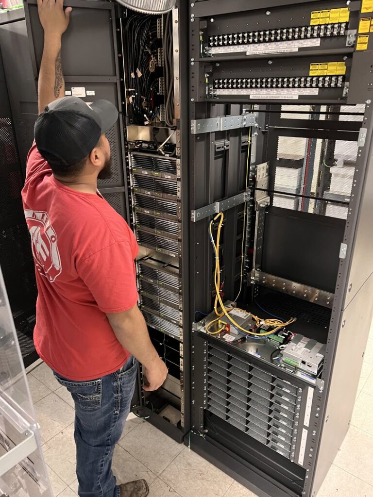 An electrician from Mario Electric working on a server rack or electrical panel in San Antonio, TX.