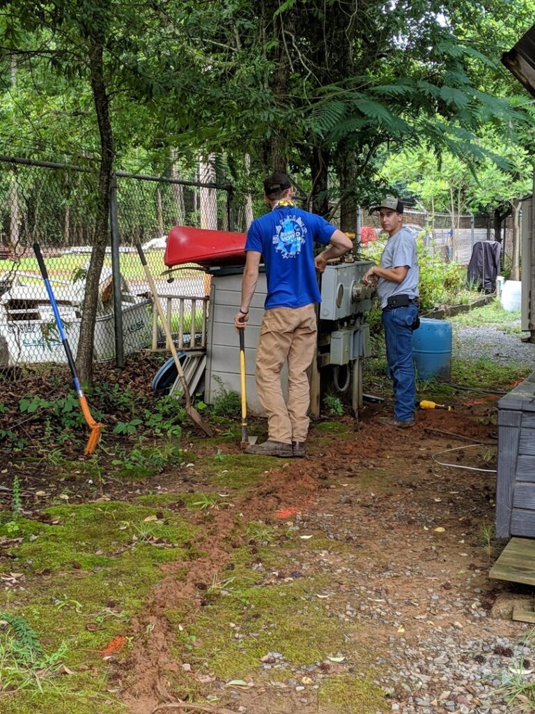 An electrician on a ladder working on the electrical service entrance of a house for Starnes Electric LLC in Rock Hill, SC.