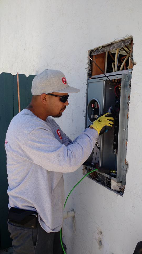 An electrician from Premo Electric working on an outdoor electrical service panel in Spring Valley, CA