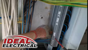An electrician from Ideal Services NW in Fife, WA, working on a terminal block with multiple wires in an electrical panel.