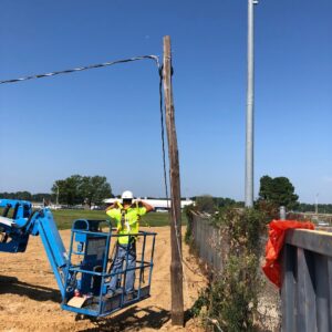 An electrician from Rush Electric Memphis, TN, working on utility pole wiring from a lift bucket under a clear sky.
