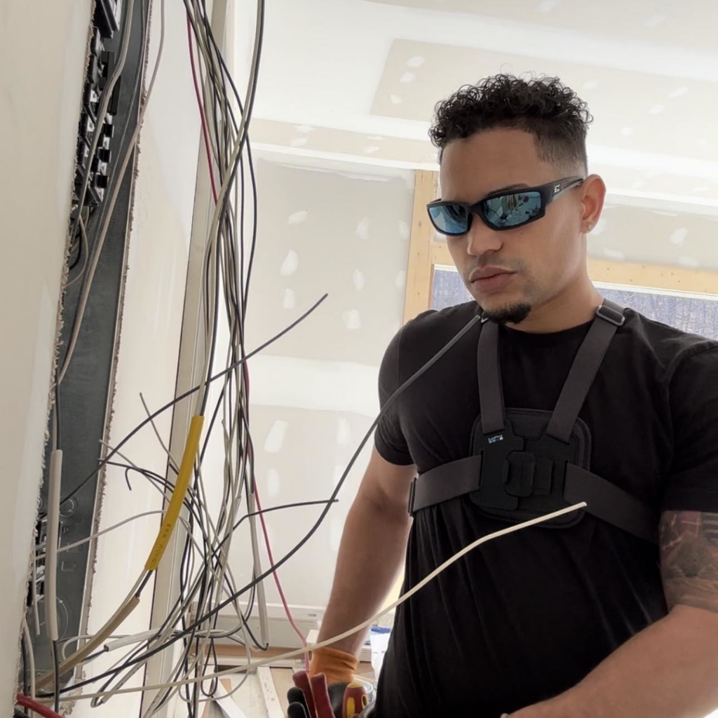 An electrician from Alta Electrical LLC working on complex wiring inside a wall in Greer, SC