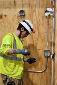 An electrician working on electrical wiring in a wall-mounted box at MetroPower, Inc. in Albany, GA.