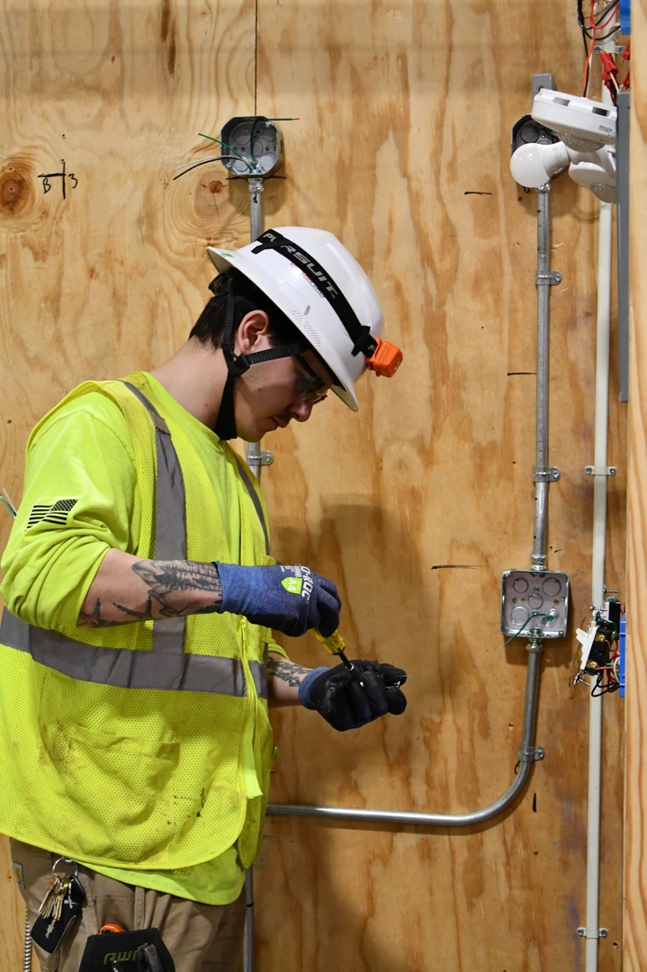An electrician working on electrical wiring in a wall-mounted box at MetroPower, Inc. in Albany, GA.