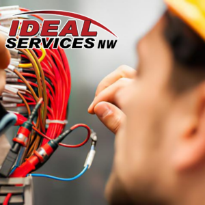 A close-up of an electrician from Ideal Services NW in Fife, WA, working on complex wiring in an electrical box.