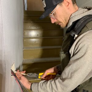 An electrician from Grason Electric working on electrical wiring coming out of a wall in Fort Collins, CO.
