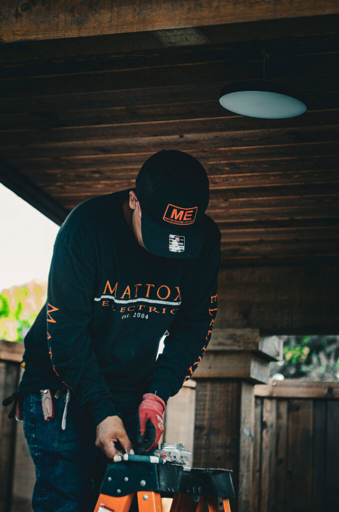 An electrician from Mattox Electric, LLC in Dallas, TX, working on an electrical wiring installation while standing on a ladder.