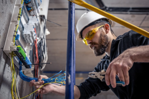 An electrician in a hard hat and safety glasses working on electrical wiring at J. K. Quality Electric in Saint Bernard, LA.