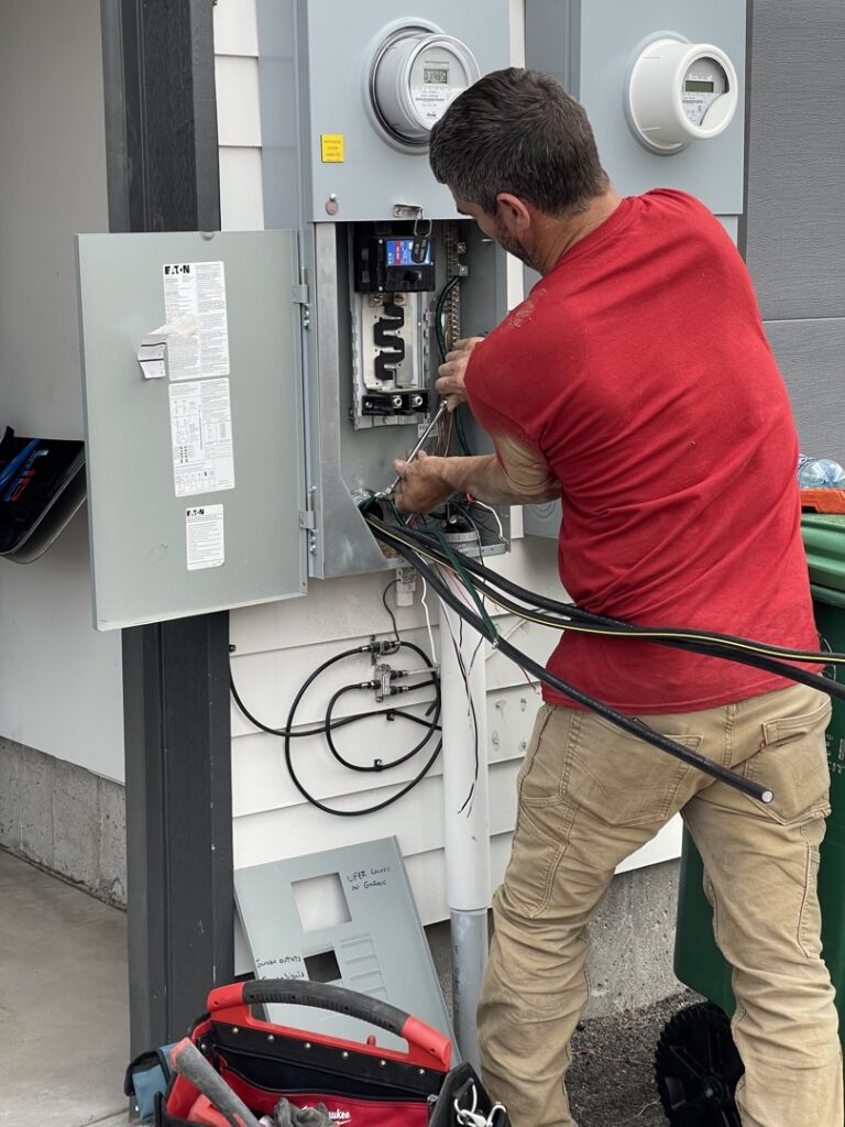 An electrician working on an outdoor electrical meter and service panel for Flowers Electric in Aurora, CO.