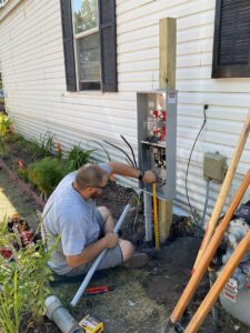 An electrician working on an outdoor electrical meter box and panel for LeBrun Electric, Heating & Cooling in Brooklyn Park, MN.