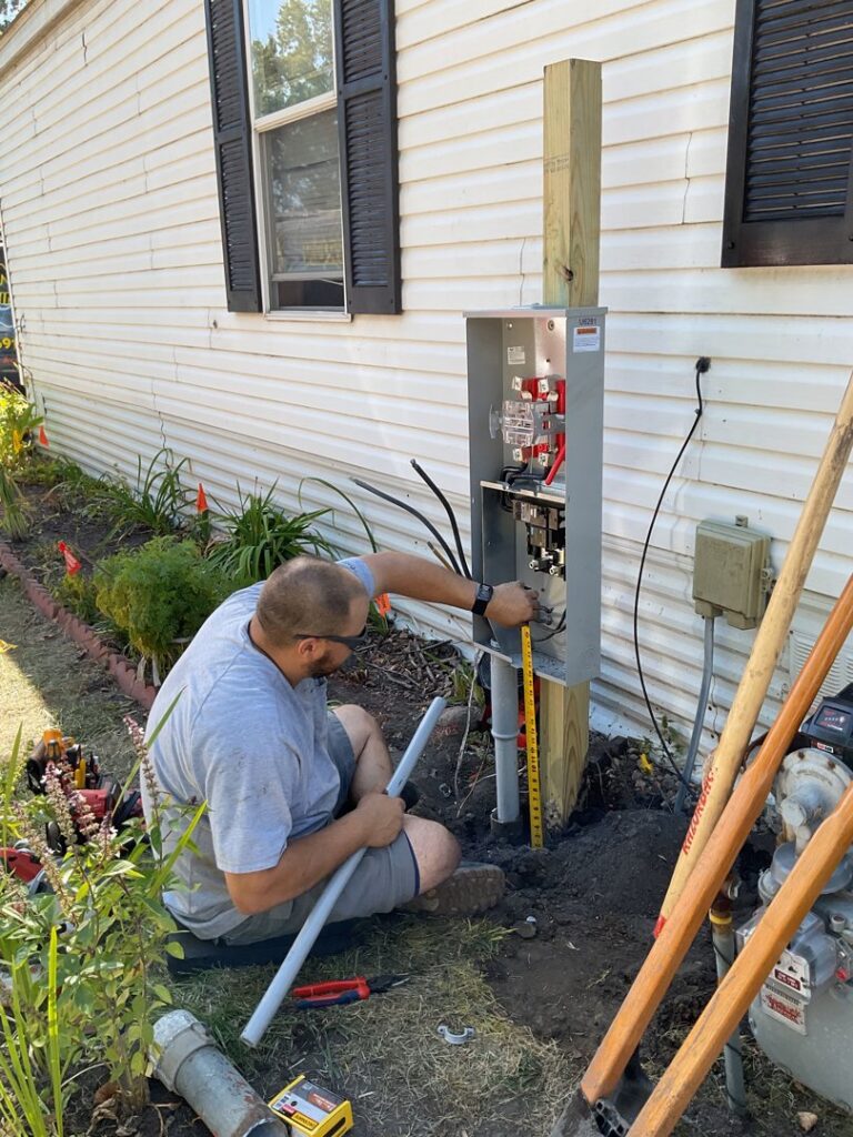 An electrician working on an outdoor electrical meter box and panel for LeBrun Electric, Heating & Cooling in Brooklyn Park, MN.